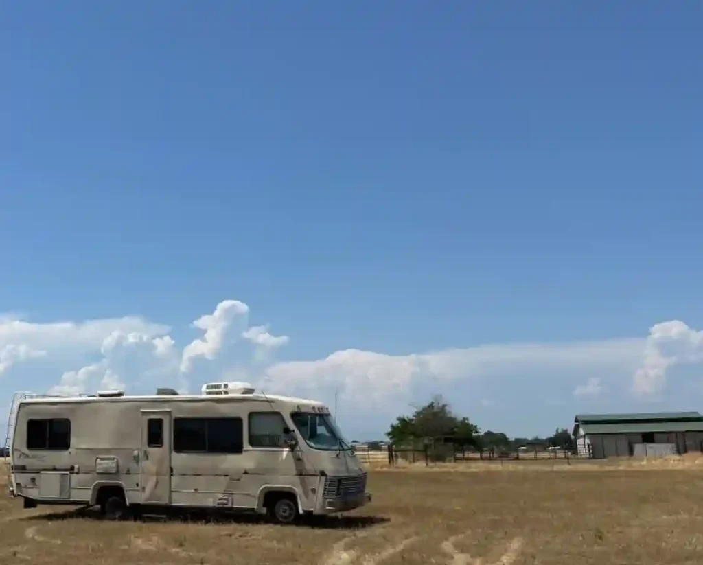 Old RV motorhome sitting unused in an open field waiting for removal
